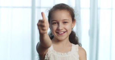 Kafkasyalı mutlu, sarışın, pozitif çocuk kameraya bakıyor başparmağınızı kaldırın ve onaylayın. Güzel, güzel, güzel, duygusal, tavsiye verici her şeyi yapın.