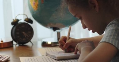 Akıllı ilkokul çocuğu matematik ödevi yapmayı öğreniyor. Evde oturuyor, sevimli, küçük bir anaokulu çocuğu tek başına çalışıyor. Notlar alıyor, ilköğretim konsepti geliştiriyor.