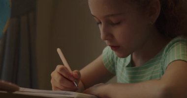 Akıllı ilkokul çocuğu matematik ödevi yapmayı öğreniyor. Evde oturuyor, sevimli bir anaokulu çocuğu tek başına ders çalışıyor. Çocukların ilkokul konsepti. 4K