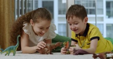 İki sevimli çocuk komik erkek ve kız kardeş dinozor oynuyorlar. Küçük çocuklar paleontolojinin evde birlikte eğlendiğini anlatıyor. İki arkadaş canlısı küçük kardeş oturma odasında oyuncak oyunu oynuyor. 4K.