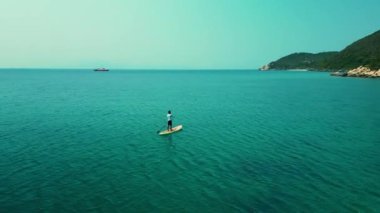 Yaz tatilinde su sporu yapan bir adam. Aktif turizm ve seyahat kavramı. Kürekli bir adamın havadan görünüşü dağlarda, denizde yemek masasında..
