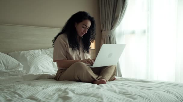 ベッドルームのノートパソコンの自宅のオフィスに入力すると 深刻な女性はチャットにノートパソコンを使用しています — ストック動画