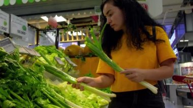 Pembe takım elbiseli çekici genç kadın lahana salatası seçiyor, süpermarketten alışveriş yapıyor, bakkaldan sağlıklı yiyecekler alıyor, marketten lahana salatası alıyor, süpermarketten. Market alışverişi kavramı