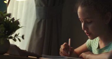 Akıllı ilkokul çocuğu matematik ödevi yapmayı öğreniyor. Evde oturuyor, sevimli bir anaokulu çocuğu tek başına ders çalışıyor. Çocukların ilkokul konsepti. 4K