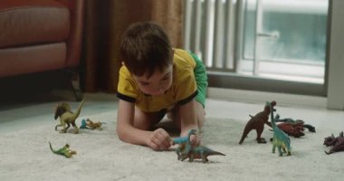 Dinozorculuk oynayan sevimli çocuk komik küçük çocuk. Küçük çocuk evde eğlenen paleontolojiyi anlatıyor. Küçük kardeş çocuklar oturma odasında oyuncak oyunu oynuyorlar. 4K.