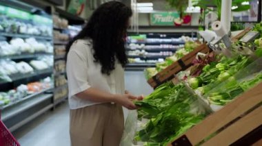 Pembe takım elbiseli çekici genç kadın lahana salatası seçiyor, süpermarketten alışveriş yapıyor, bakkaldan sağlıklı yiyecekler alıyor, marketten lahana salatası alıyor, süpermarketten. Market alışverişi kavramı