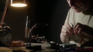 Çoklu metre kullanan biri, devrede açık devre arayan bir mikro devre üzerinde çalışıyor. Elektrikçi mikro devreyi kontrol eder, mikro devreyi elektirikli multimetre kullanarak test eder..
