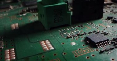 Makro kamera, bilgisayar ana kartı bileşenlerini, mikroçipi, işlemciyi ve transistörleri göstererek basılı devre kartının üzerinde yavaşça hareket ediyor. Elektronik cihazın içinde CIP 'li süper bilgisayar devreleri var.