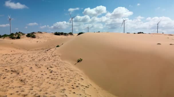 明るい晴れた日の鳥の目のビューからオレンジの砂漠で青い空と白い雲に対してブレードと大型風力タービン 風車のシルエット 代替エネルギー — ストック動画