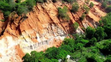 Ağaçlı turuncu kanyonun üst manzarası, dağlarda turuncu arazi, yavaş çekim drone dönüşü. 4K.