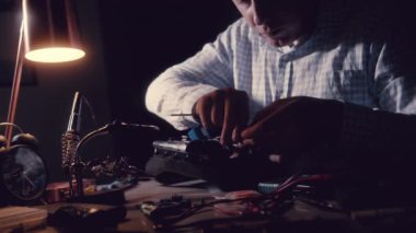 Ev aletlerinin erkek portresi, hava pompasını tamir eden bir adam, tornavida ve diğer aletlerle elektro-pnömatik bir cihazı söker. Erkekler atölyede çalışıyor. 4K.