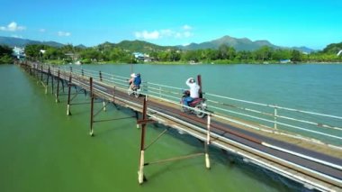 Ormandan yola doğru tahta bir köprüde motorsikletle giden hava manzaralı motorcular. Motosikletliler yeşil ahşap yolda onun motosikletini sürüyorlar. Yolculuk sırasında bisiklet süren bir adam. Özgürlük ve macera