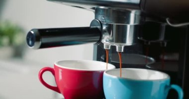 Kahve makinesinden fincanlara kahve dökülüyor. Ev yapımı sıcak Espresso. Filtre tutacağı kullanılıyor. Taze kahve akıyor. Sabahları kavrulmuş sade kahve içmek..