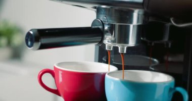Kahve makinesinden fincanlara kahve dökülüyor. Ev yapımı sıcak Espresso. Filtre tutacağı kullanılıyor. Taze kahve akıyor. Sabahları kavrulmuş sade kahve içmek..
