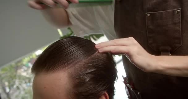 理发师用喷雾把头发弄湿 然后梳理它 时髦的男人正坐在理发店里 理发师女人剪头发 迷人的男人在一家现代理发店理发 — 图库视频影像