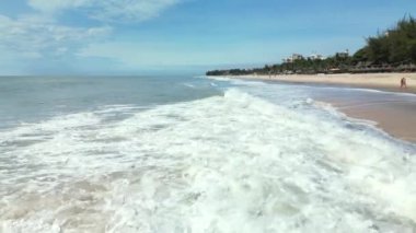 Deniz dalgaları kumlu sahil şeridinde dalgalanırken hiç bitmeyen güzel ve kusursuz görüntülerin drone görüntüsü. Altın plajın, derin mavi okyanus suyu ve köpüklü dalgalarla buluşmasının havadan çekimi. 4K.