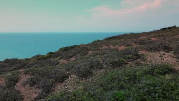 海水清澈清澈的群山中 绿色能源的生命力 绿草的顶视图 然后是悬崖面 俯瞰着五彩缤纷的大海 在岩石和风景如画的海岸线上旋转着 — 图库视频影像