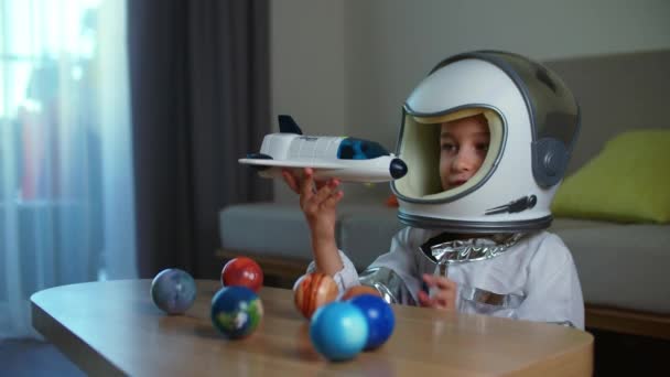 一个孩子穿着航天员的衣服在家里玩耍 一个8 9岁的小女孩戴着玩具太空头盔的滑稽画像 一个微笑着看着相机的孩子 一个特写 一个飞向太空的飞行员 — 图库视频影像
