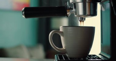 Kahve makinesinden fincana kahve dökülüyor. Ev yapımı sıcak Espresso. Filtre tutacağı kullanılıyor. Taze kahve akıyor. Sabahları kavrulmuş sade kahve içmek. 4K.
