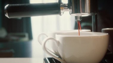 Kahve makinesinden fincana kahve dökülüyor. Ev yapımı sıcak Espresso. Filtre tutacağı kullanılıyor. Taze kahve akıyor. Sabahları kavrulmuş sade kahve içmek. 4K.