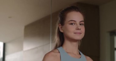 Bir fitness kızı portresi, spor salonunda kız kameraya olumlu bir şekilde bakıyor. Spor salonundaki spor eğitimine olumlu yaklaşım. Spor kulübündeki kadın. 4K