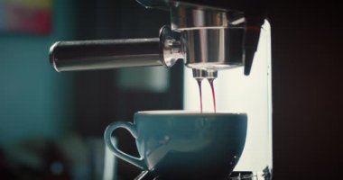 Bir makineden mavi bir fincana kahve dökmek. Ev yapımı sıcak espresso. Bir filtre tutucu kullanarak. Taze öğütülmüş kahve akar. Sabahları kavrulmuş sade kahve içerim. 4K.