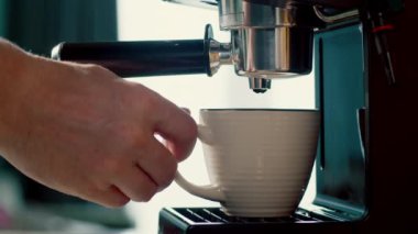 Kahve makinesinden fincana kahve dökülüyor. Ev yapımı sıcak Espresso. Filtre tutacağı kullanılıyor. Taze kahve akıyor. Sabahları kavrulmuş sade kahve içmek. 4K.
