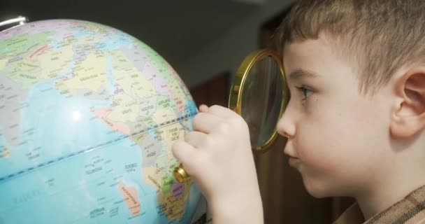 귀여운 살짜리는 돋보기를 지구본을 봅니다 학생을 아이는 지구본을 봅니다 아이는 — 비디오