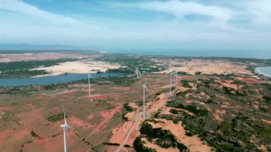 Geniş rüzgar türbinleri. Saha manzaralı, parlak turuncu günbatımı. Mavi gökyüzü parkı yavaş çekim drone dönüşü. Siluetler yel değirmenleri, büyük turuncu güneş diski yaz merceği parlamaları. Alternatif enerji
