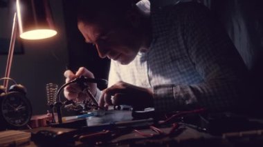 Bir mikro devreyi tamir etmek, lehimleme demiri dumanı. Telsiz bileşenlerini sökmek. Değerli metal, altın rengi lehimler. Transistörler, Elektronik Tahtada lehimli Radyo Elektronik Parçalar.