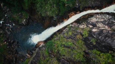 Vietnam 'da inanılmaz güzel bir şelale, suyun yüzeyine düşen sular, çerçevenin önünde devasa taşlar görünüyor. Bereketli yeşil yapraklar rüzgardan, Vietnam 'dan geliyor. 4K.