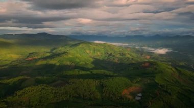 Dağlar arasındaki güzel tropikal vadilerin hava aracı hiperlapse zamanlaması. Yükselen güneşin ilk ışınları bulutları ve bulutları delip geçer. Gün batımının son ışınları ağaca vurdu.
