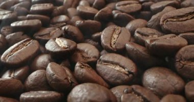 Makro fırında kahve çekirdeği vurdu. Aromatik kahve çekirdekleri kahve çekirdeklerinin kızartılışından çıkan koyu renkli dumanların içinde yavaşça hareket eder. Kavrulmuş kahve çekirdeklerini dumanla yakın plan çek.