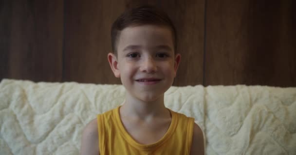 Portret Zabawny Mały Chłopiec Uśmiechnięty Dziecko Patrząc Aparat Siedzą Kanapie — Wideo stockowe