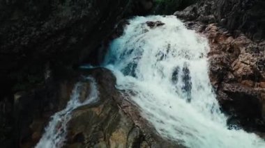 Vietnam 'da inanılmaz güzel bir şelale, suyun yüzeyine düşen sular, çerçevenin önünde devasa taşlar görünüyor. Bereketli yeşil yapraklar rüzgardan, Vietnam 'dan geliyor. 4K.