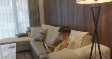 Çocuk 4-5 yıldır oturma odasında tablet kullanmaktan korkuyor, küçük çocuk kucağında bilgisayar sörfü ev konseptinde güvenli olmayan internet, sosyal medyada ebeveyn güvenliği çocuğu