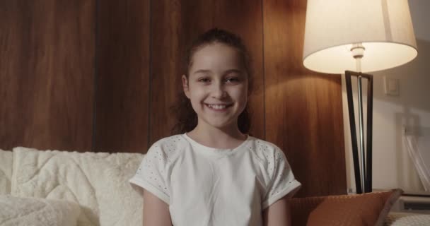 Портрет Смішна Дівчинка Усміхнена Дитина Дивлячись Камеру Сидить Дивані Вдома — стокове відео