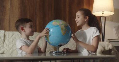 Çocuklar gün batımında evde otururken ders çalışıyor. Çocuklar sabah gün batımında Globe, tatlı oğlan ve küçük kızla, okul çocukları için teknoloji, çocuk dünyaya bakıyor.