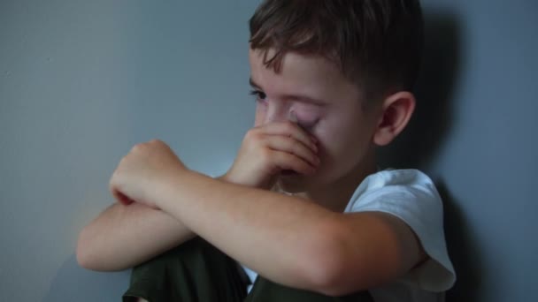 頬に大きな涙を浮かべてかわいい男の子の肖像画 悲しい動揺の少年は隅に座って生活様式 家庭内暴力の概念 児童虐待 — ストック動画