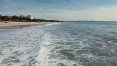 Deniz dalgaları kumlu sahil şeridinde dalgalanırken hiç bitmeyen güzel ve kusursuz görüntülerin drone görüntüsü. Altın plajın, derin mavi okyanus suyu ve köpüklü dalgalarla buluşmasının havadan çekimi. 4K.