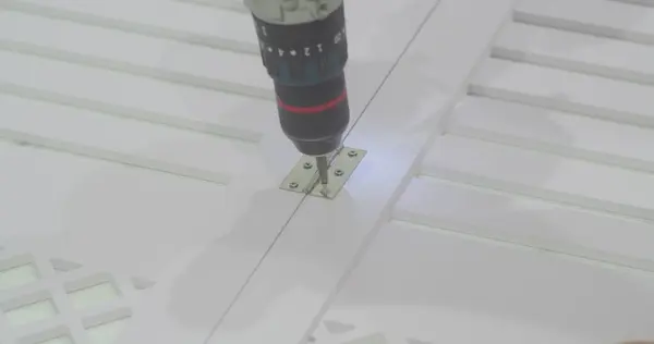 Elektrikli tornavida kullanan bir adam tahtaya vida takıyor. Makro. Yakın plan..