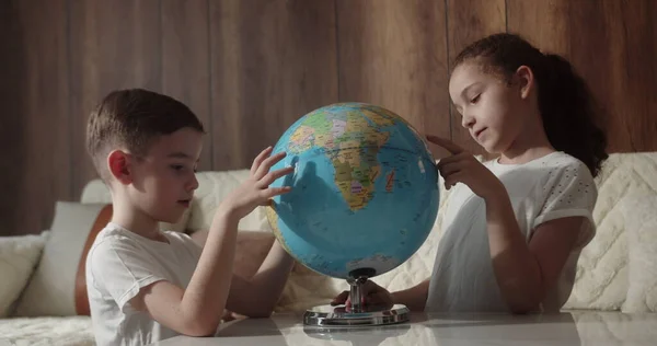 Çocuklar gün batımında evde otururken ders çalışıyor. Çocuklar sabah gün batımında Globe, tatlı oğlan ve küçük kızla, okul çocukları için teknoloji, çocuk dünyaya bakıyor.