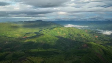 Dağlar arasındaki güzel tropikal vadilerin hava aracı hiperlapse zamanlaması. Yükselen güneşin ilk ışınları bulutları ve bulutları delip geçer. Gün batımının son ışınları ağaca vurdu.