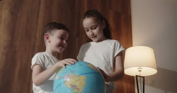 Çocuklar gün batımında evde otururken ders çalışıyor. Çocuklar sabah gün batımında Globe, tatlı oğlan ve küçük kızla, okul çocukları için teknoloji, çocuk dünyaya bakıyor.