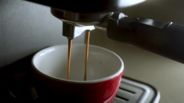 Kahve makinesinden fincana kahve dökülüyor. Ev yapımı sıcak Espresso. Filtre tutacağı kullanılıyor. Taze kahve akıyor. Sabahları kavrulmuş sade kahve içmek..