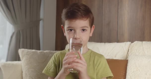 笑顔の子供がミルクを飲んでいる 朝食を食べる子供を健康的に食べる子供の夢の概念 リビングルームの息子はヨーグルトミルクを飲んで唇を許可する ポジティブな子供 朝食を持っている — ストック動画