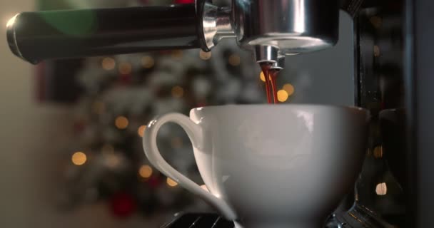 機械からカップに注ぐコーヒーのショットロール 自家製ホットカプチーノクリスマスツリーとクリスマスライトの背景 地上のコーヒーフロー 朝から飲む — ストック動画
