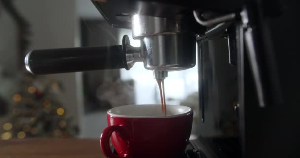 Rouleau de café coulant d'une machine dans une tasse. Cappuccino chaud fait maison sur fond d'arbre de Noël et de lumières de Noël. Du café fraîchement moulu coule. Le matin, je bois