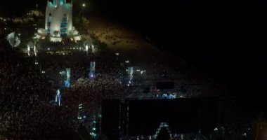 Konser atmosferi bulanık, tanınmayan hayranlar ellerinde el fenerleriyle sahne önünde cep telefonları tutuyorlar.