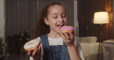 Pembe jöleli tatlı çörek mi yoksa beyaz çikolatalı mı yiyeceğine karar veremeyen 11 yaşındaki mutlu bir çocuğun portresi. Beyaz bir çocuğun tatlı hamur işleri yediği yakın plan. 4K